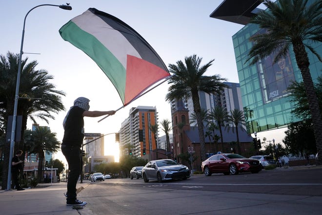 A demonstrator waves a Palestinian flag as cars drive by along University Avenue while ASU students and supporters gather at the universityÕs campus to show their support for Palestinians amid the Israel-Hamas war on Apr 26, 2024.